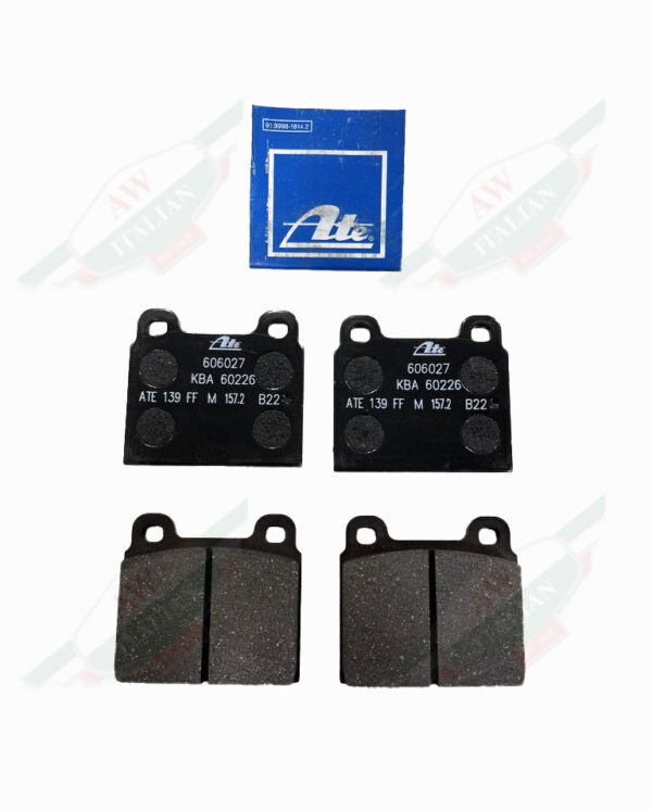 four black square metal brake pads beneath square blue paper on white background